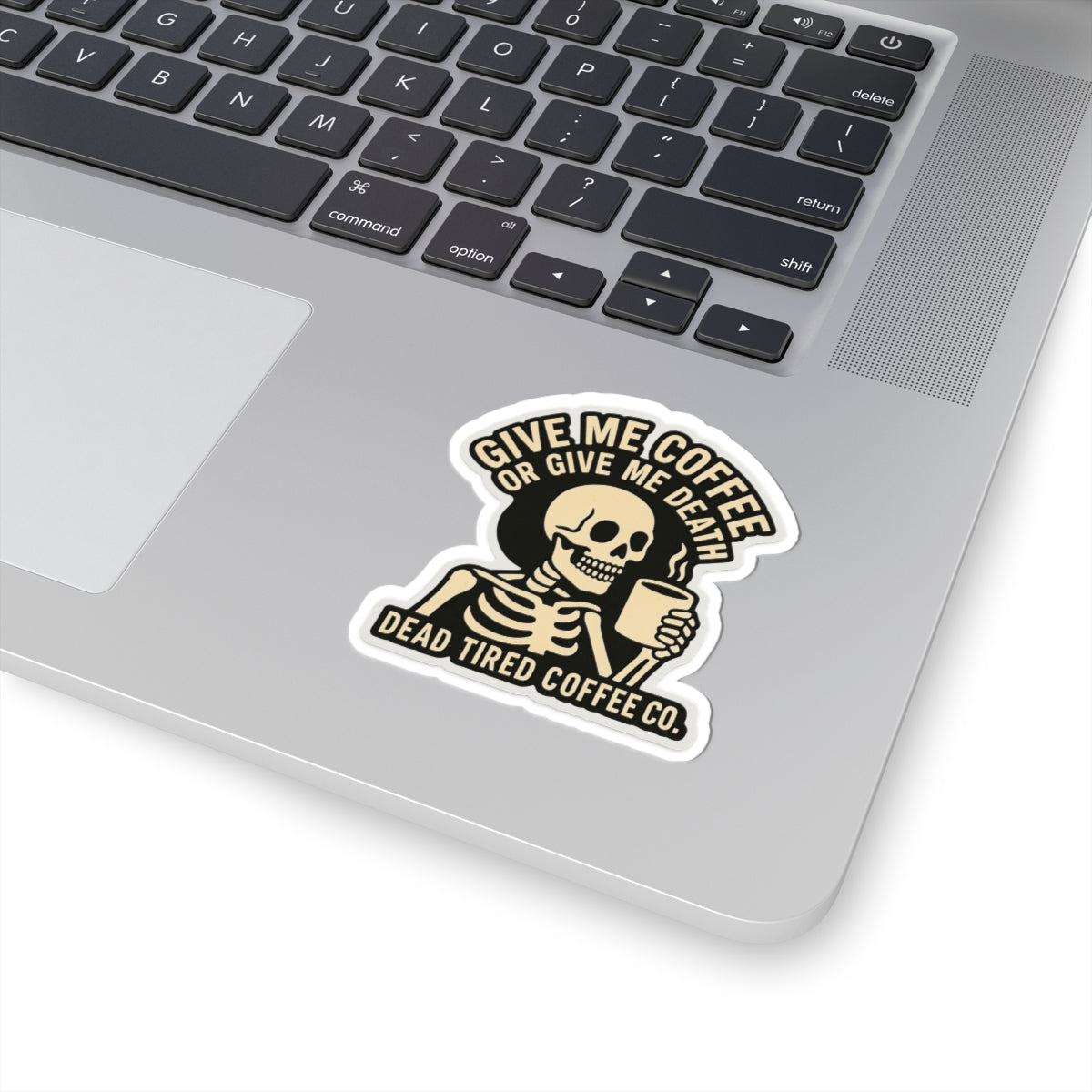 Laptop with a skeleton holding a coffee cup sticker on the palm rest area.
