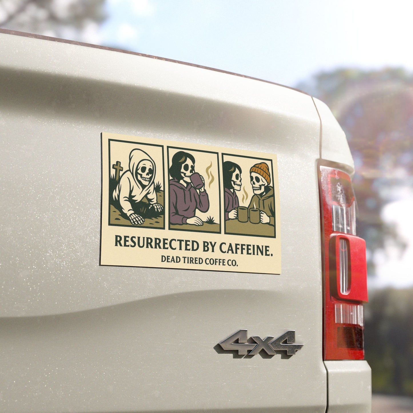 Sticker on a car's rear window with cartoon skeletons and text 'Resurrected by Caffeine' on a blurred natural background.