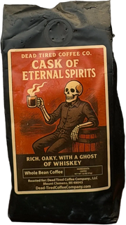 Cask of Eternal Spirits coffee bag by Dead Tired Coffee Co. The rust-red label shows a skeleton raising a steaming mug beside a barrel, a nod to its whiskey barrel-aged Guatemala coffee.