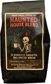 Haunted House coffee bag by Dead Tired Coffee Co. Its dark label shows a skeleton holding a steaming mug before a haunted house; inside is medium roast, single-origin Peru coffee.